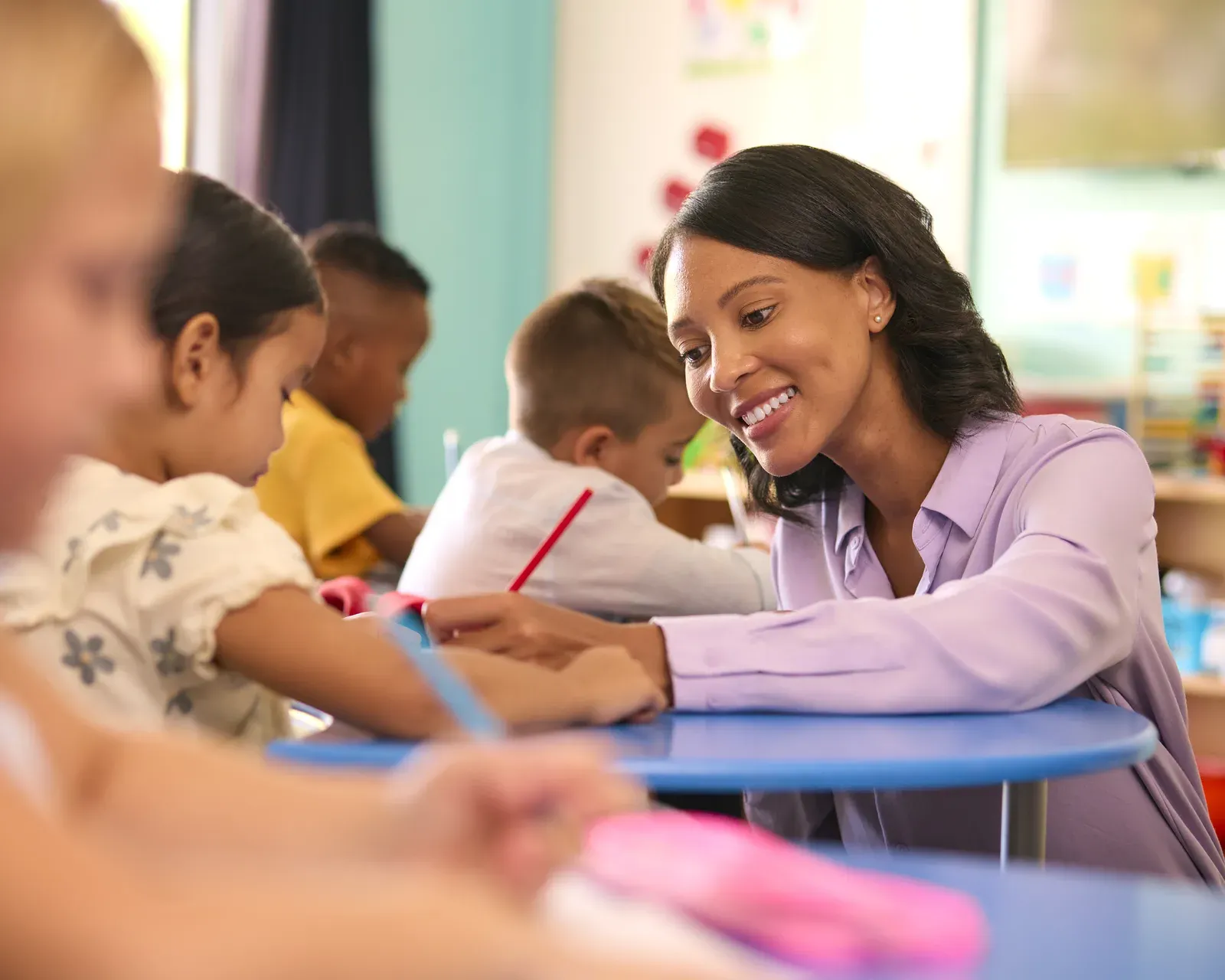 Teacher guiding a child in a warm, playful classroom